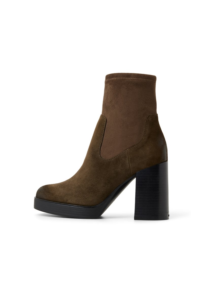 Botines de ante marrón con una parte superior ajustada, un tacón grueso negro y punta redondeada. Presenta paneles elásticos laterales para un fácil calce.