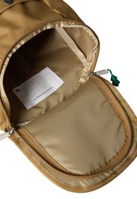 Bėgiškas smėlio spalvos kuprinės vidus su lygia, blizgia pamušalu; yra kišenė su užtrauktuku ir audinio etiketė su tekstu. Kraštai sutvirtinti siūle.