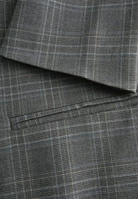 Sivna tkanina z diskretnim karo vzorcem in finimi modrimi črtami, ki prikazuje posnetek prekrivajočih se zloženih tekstilnih plasti.