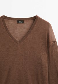 Brązowy sweter z kaszmiru z dekoltem w kształcie litery V, fakturowanym splotem i luźnym krojem. Metka z napisem "Massimo Dutti" na dekolcie.