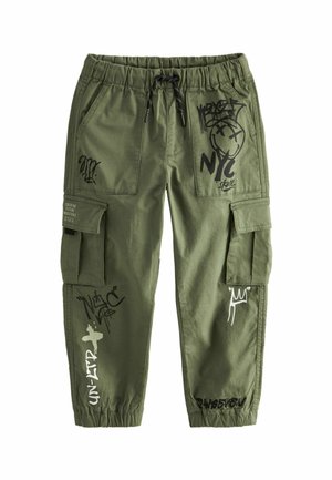 Olive green cargo pants with elastic waistband, black drawstring, side pockets, and black and white graffiti-style prints on legs and pockets.