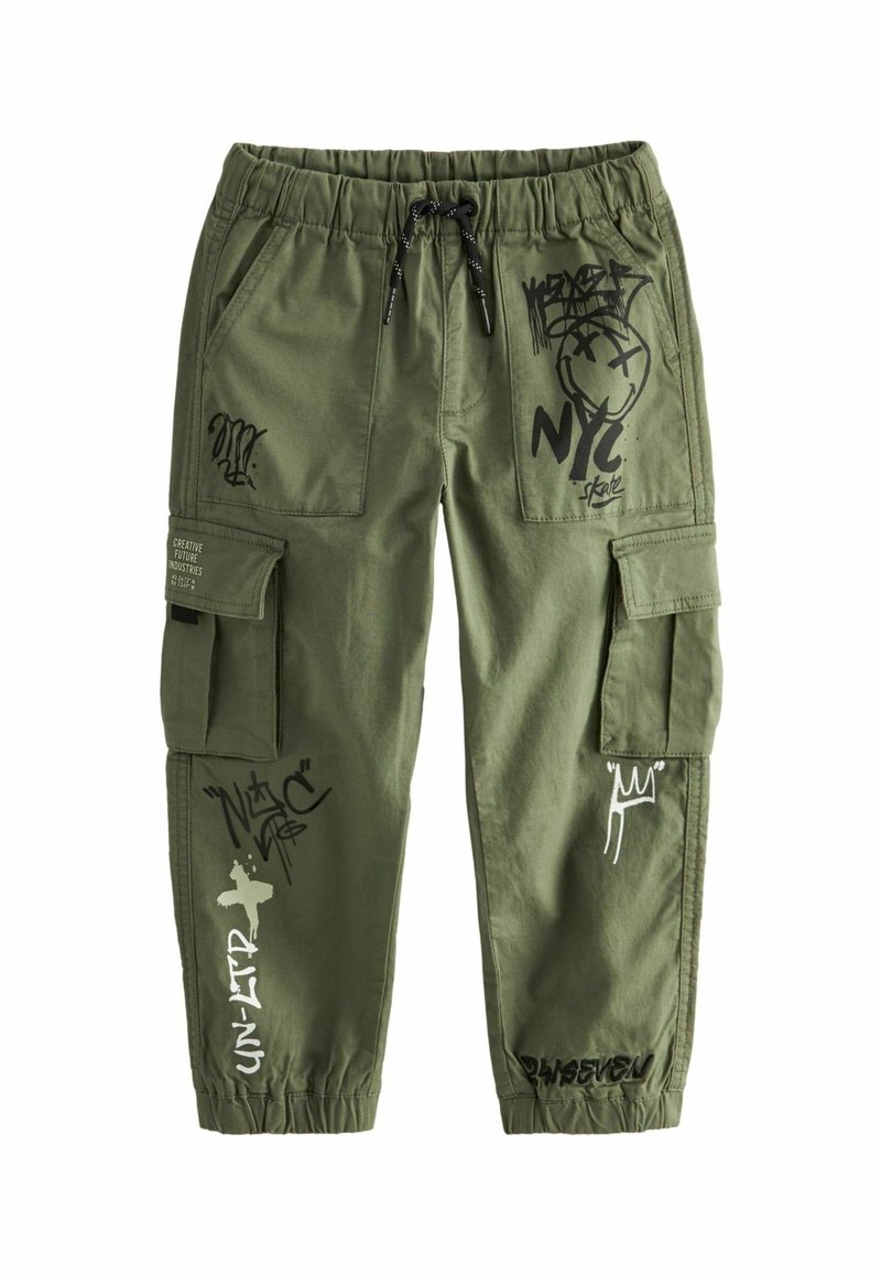 Pantalon cargo vert olive avec taille élastique, cordon de serrage noir, poches latérales et imprimés style graffiti en noir et blanc sur les jambes et les poches.