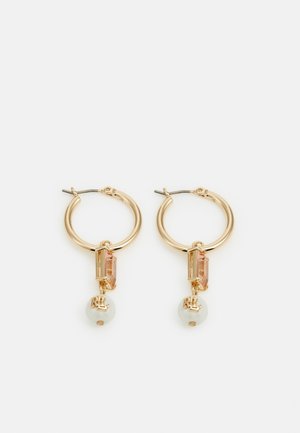 Goldene Creolen mit rechteckigen pinkfarbenen Edelsteinen und weißen Perlen, graviert mit Initialen, auf weißem Hintergrund präsentiert.