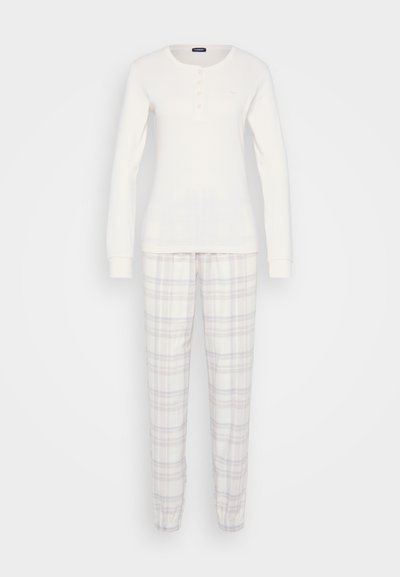 Camisola de manga longa em bege claro com botões, combinada com calças xadrez em branco, lavanda e cinza. Ambos feitos de tecido macio.