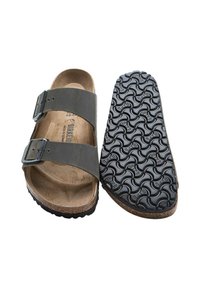 Svart lädersandaler med två justerbara spännen, korkfotbädd och en texturerad svart gummisula med ett vågmönster.