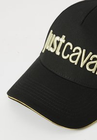 Boné de beisebol preto com texto bordado branco "ballistcava" e detalhes amarelos ao longo da borda da aba.