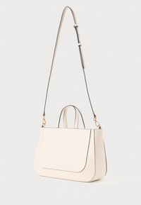 Sac en cuir couleur crème avec des bords arrondis, deux poignées supérieures et une bandoulière amovible. Caractéristiques en métal doré et un passepoil contrastant.