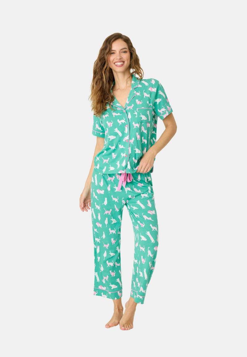 Kortärmade, knäppbara pyjamas i teal med vita och rosa kattmönster, med rosa detaljer och lösa byxor.