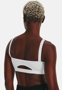 Sutiã desportivo branco com alças ajustáveis, detalhe com recorte nas costas e um design elegante e ajustado feito de tecido texturizado.
