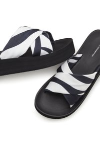 Black platform slide sandals featuring a cross-over strap design in white and navy striped fabric. Smooth matte finish and textured sole.