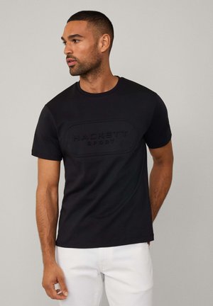 T-shirt en coton noir avec un logo en relief "HACKETT SPORT" sur le devant, col rond et manches courtes. Texture lisse.