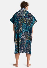 Mønstret hætteponcho i mørkeblå, der har geometriske former i teal og guld. Blødt stof med vide ærmer og knælængde design.