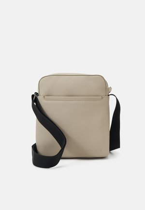 Beige olkalaukku, jolla on sileä matta pinta, suorakaiteen muotoinen, säädettävä musta hihna ja etupuolella vetoketjullinen tasku. Merkitty "PIER ONE."