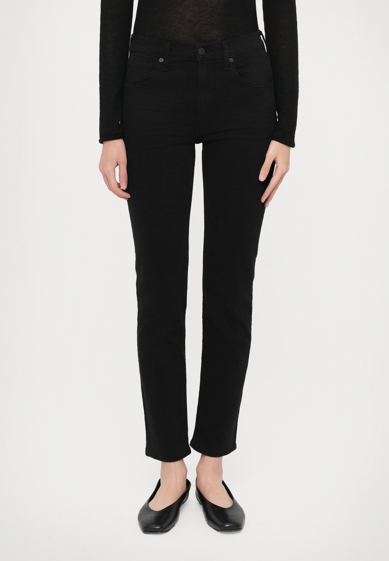 Μαύρα skinny τζιν με ψηλή μέση, διαθέτουν φερμουάρ σ�το μπροστινό μέρος και τσέπες. Συνδυασμένα με μαύρα φλατ παπούτσια, το ύφασμα φαίνεται λείο και ελαστικό.