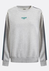 Sudadera gris de manga larga, con cuello redondo, que presenta franjas laterales en turquesa y negro y el logotipo "GUESS 1981" en el pecho. Textura suave.