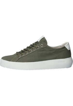 Zapatilla de lona verde con suela de goma blanca, puntera redondeada, ojales de metal y acento blanco en el talón. Presenta detalles cosidos y material texturizado.