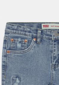 Jeans ajustados Levi's 510 en mezclilla ligera, con detalles desgastados, herrajes de cobre y un diseño clásico de cinco bolsillos.