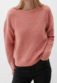 Rosa stickad tröja med ribbat mönster, bred halsringning och långa ärmar, kombinerad med svarta byxor. Har en avslappnad passform och en mjuk finish.