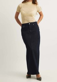 Dunkelblaue Maxi-Rock mit gerader Silhouette, fünf Taschen und silbernem Zubehör. Kombiniert mit einem leichten, figurschmeichelnden Ripp-Top.
