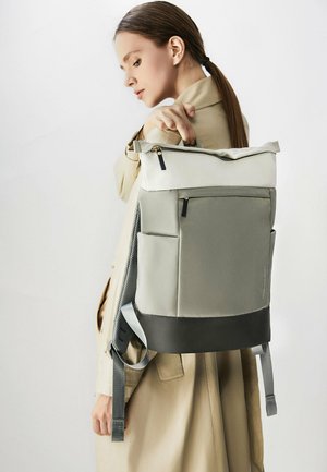 Zaino grigio e nero con design a chiusura arrotolata, tasca laterale e spallacci regolabili. Realizzato in tessuto resistente con una texture liscia.