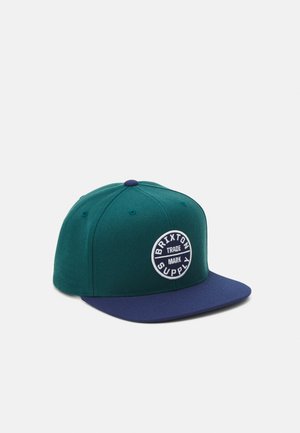 Czapka snapback w kolorze morskim i granatowym z okrągłą naszywką z logo "Brixton Supply Trade Mark" na przednim panelu.