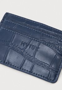 Porte-cartes en cuir texturé bleu marine avec motif crocodile, comportant plusieurs emplacements pour cartes et le nom de marque embossé "HVISK."