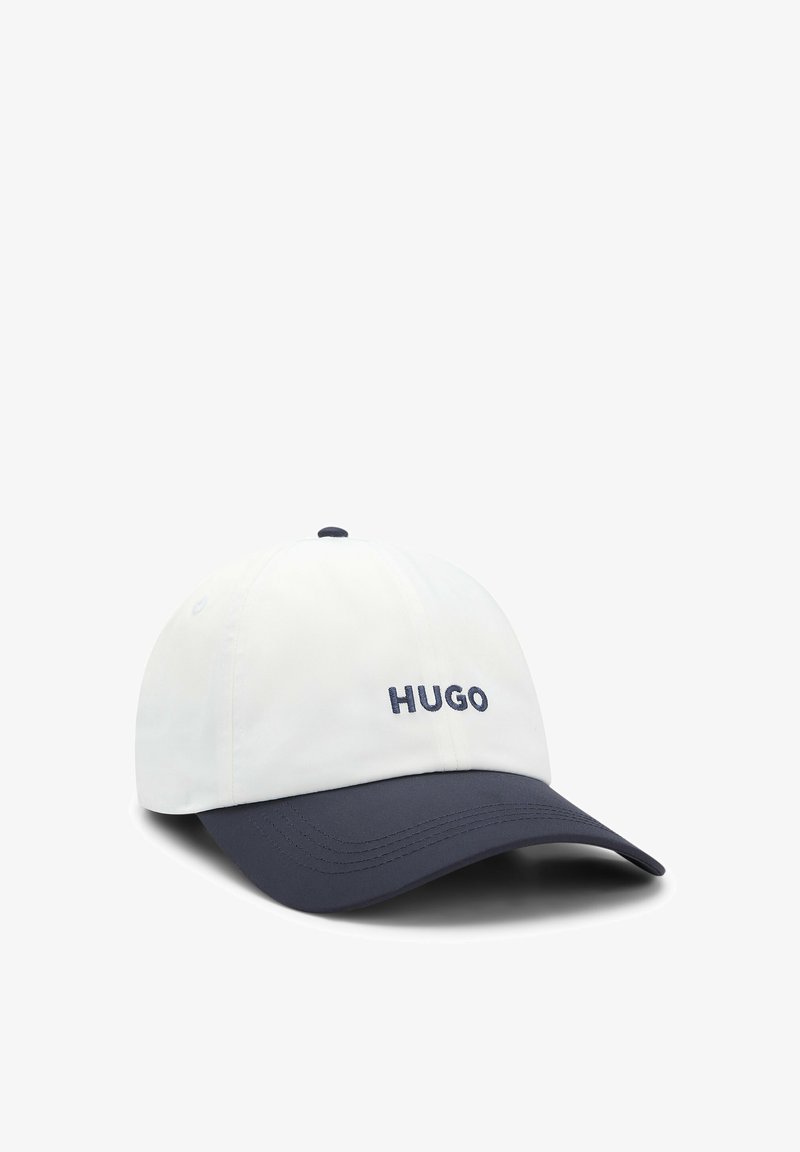 Casquette de baseball blanche avec une visière courbée bleu marine et « HUGO » brodé en bleu marine sur le panneau avant.