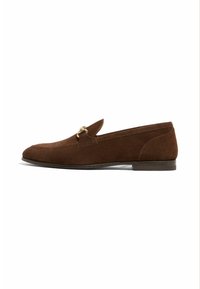 Bruine nubuck instapper met een ronde neus, een slip-on ontwerp en een klein accent van goudkleurig metaal. Platte zool, minimale stiksels en een gladde textuur.