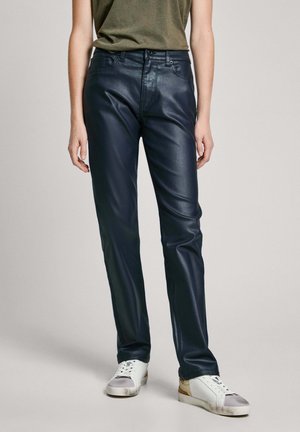 Pantalones de símil cuero azul marino con un corte recto, que cuentan con una bragueta de botón, diseño de cinco bolsillos y se llevan con zapatillas blancas. Textura suave.