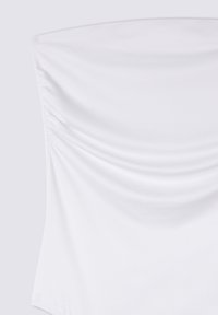 Top bianco realizzato in un tessuto morbido e elasticizzato, con dettagli arricciati lungo i lati che creano una silhouette strutturata e una texture sottile.