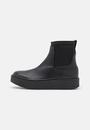 Schwarzer Leder-Stiefel mit dicker strukturierter Sohle und elastischem Seitenpaneel, mit subtiler Calvin Klein-Prägung an Manschette und Sohle.