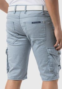 Shorts cargo en mélange de coton bleu clair avec des rayures verticales blanches. Comprend des poches latérales, une ceinture avec une boucle blanche et des coutures décoratives.