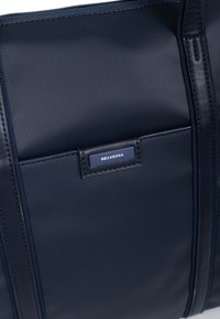 Donkerblauwe, textuurverstevigde tas van synthetisch materiaal, met een rechthoekige vorm en een klein merketiket met de tekst "HEXAGONA."