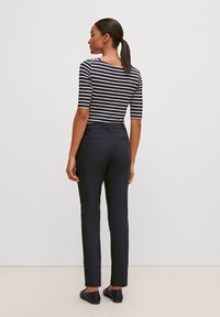 Haut ajusté rayé en bleu marine et blanc, avec des manches trois quarts, associé à un pantalon noir marine sur mesure et des chaussures plates noires.