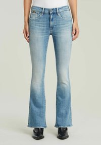 Ljust blå utfällda jeans i ett urtvättat denim-material, med fem fickor, dragkedja och sömnadsdetaljer vid midjan och nederkant.
