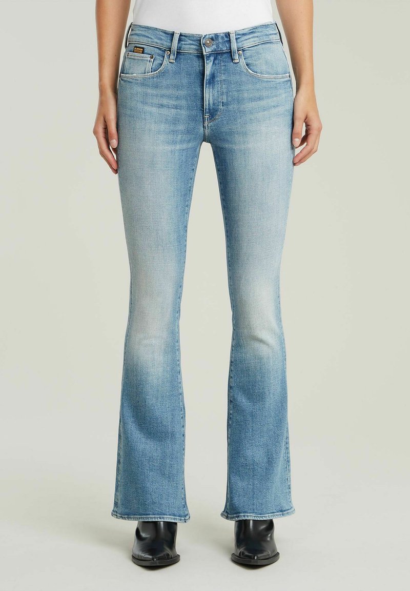 Ljust blå utfällda jeans i ett urtvättat denim-material, med fem fickor, dragkedja och sömnadsdetaljer vid midjan och nederkant.