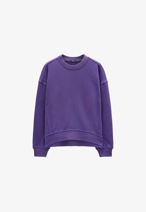 Fioletowy sweter z okrągłym dekoltem, długimi rękawami i luźnym krojem. Posiada ściągacze przy mankietach i dolnym brzegu, wykonany z miękkiego, strukturalnego materiału.