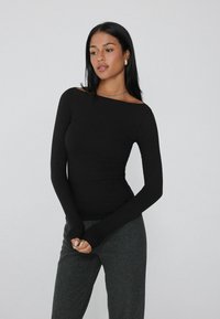 Schwarzes Langarmoberteil mit einem schulterfreien Ausschnitt. Es verfügt über einen eleganten, dehnbaren Stoff mit enger Silhouette und Daumenlöchern an den Ärmeln.