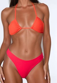Bikini a due pezzi con un top triangolare arancione brillante e slip alti rossi, realizzati in tessuto liscio e elastico.