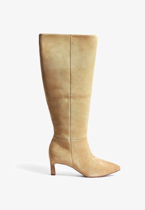 Beige Wildleder-Stiefel bis zum Knie mit spitzem Zeh und Blockabsatz. Glatte Textur, minimalistisches Design und vertikale Nahtdetails am Schaft.