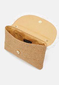 Vävd beige clutch med texturerad yta, guldknäppning och mjukt innertyg. Fransen på fliken ger en unik prägel.