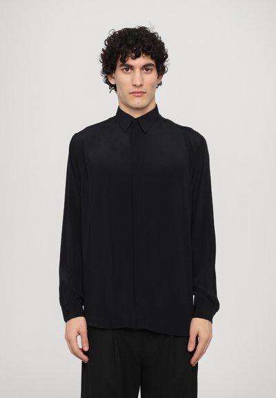 Chemise noire à manches longues en tissu lisse, dotée d'un col classique, de poignets boutonnés et d'une coupe droite.
