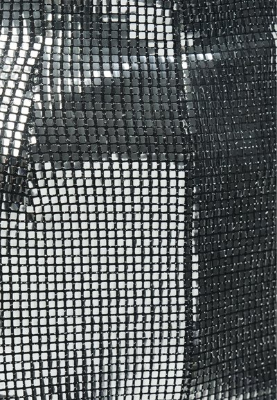 Melna acs audums ar kvadrātveida rakstu un spīdīgiem, atstarojošiem laukumiem. Faktūra šķiet gluda un nedaudz spīdīga.