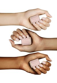 Trois mains avec des ongles manucurés, présentant un vernis à ongles rose clair. Les bouteilles sont étiquetées "essie", avec des teintes de peau variées des mains affichées.