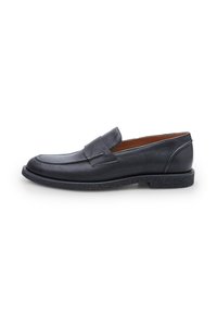 Mocasín de cuero negro con punta redondeada, parte superior texturizada, detalles cosidos y suela de goma baja y con patrón. Diseño simple y elegante.