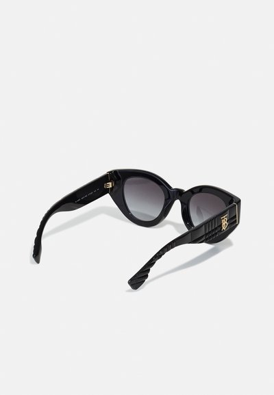 Svarta cat-eye solglasögon med gradientlinser. Strukturerade bågar har ribbad textur och en guldfärgad logotypaccents på skalmen.