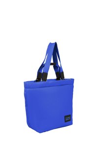 Blå isolerad bärkasse med vadderad textur, svarta accenter och två axelremmar. Har logotyppatch på sidan. Rektangulär form.