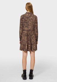 Sukienka w panterkę, z długimi rękawami, marszczonym pasem, rozkloszowanym dołem, wykonana z miękkiego materiału. Noszona z czarnymi, masywnymi botkami.