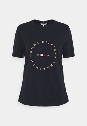 Navyblauw Tommy Hilfiger T-shirt met cirkelvormige gele tekst en een klein rood, wit en blauw logo gecentreerd op de borst.