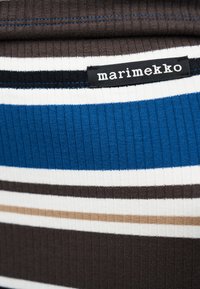 Ύφασμα με ραβδώσεις και οριζόντιες ρίγες σε καφέ, μπλε, μπεζ και άσπρο, με μια μαύρη ετικέτα που φέρει λευκό κείμενο «marimekko».